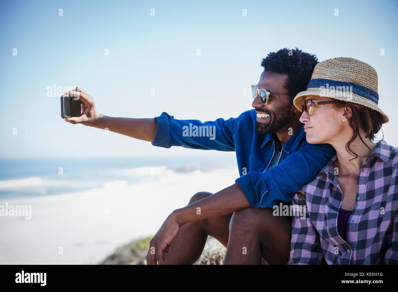 Multiethnisches Paar, das Selfie am sonnigen Sommerstrand nimmt Stockfoto