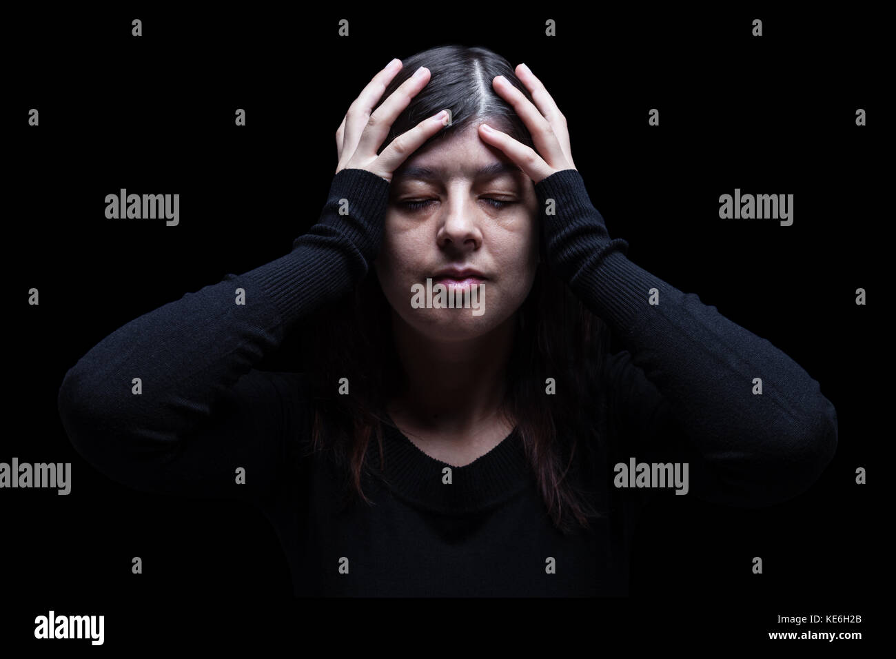 Distressed Frau mit Kopf mit Händen. schwarzer Hintergrund/Migräne Kopfschmerzen schmerzen Depression depressiven Verzweiflung Schmerz leiden Trauer Trauer stress Stockfoto