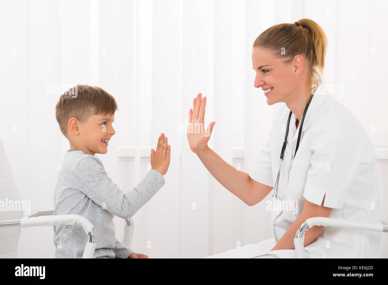 Gerne Ärztin hoch fünf zu geben Junge in Klinik Stockfoto