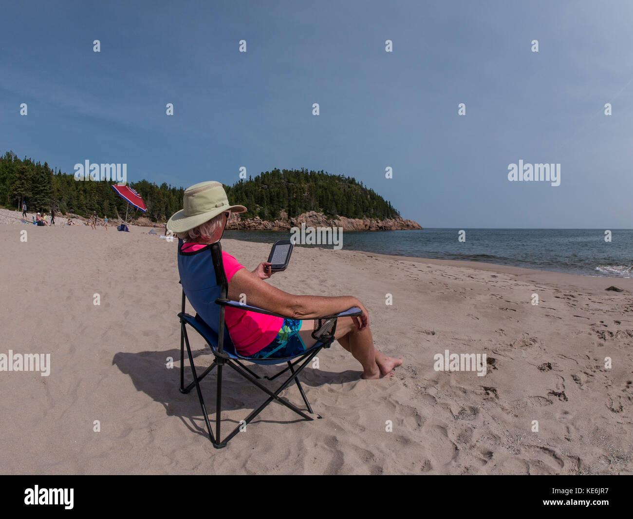 Frau liest Ihr Kindle am Strand, Schwarz Bach Cove, Cape Breton Highlands National Park, Cape Breton Island, Nova Scotia, Kanada. Stockfoto