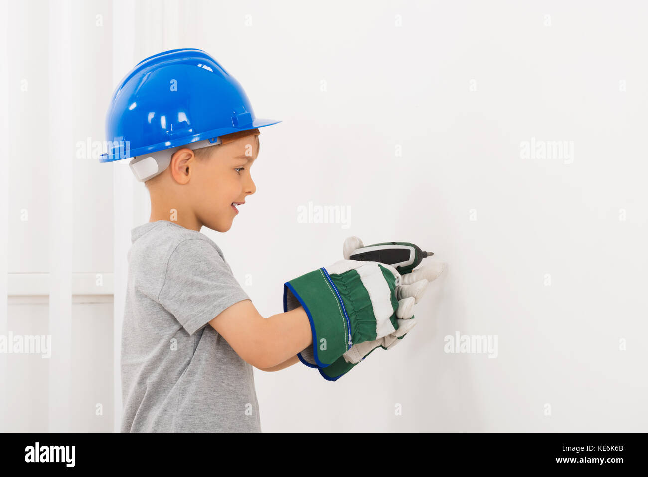 Little Boy Bohren Wand mit elektrischen Bohrmaschine zu Hause Stockfoto