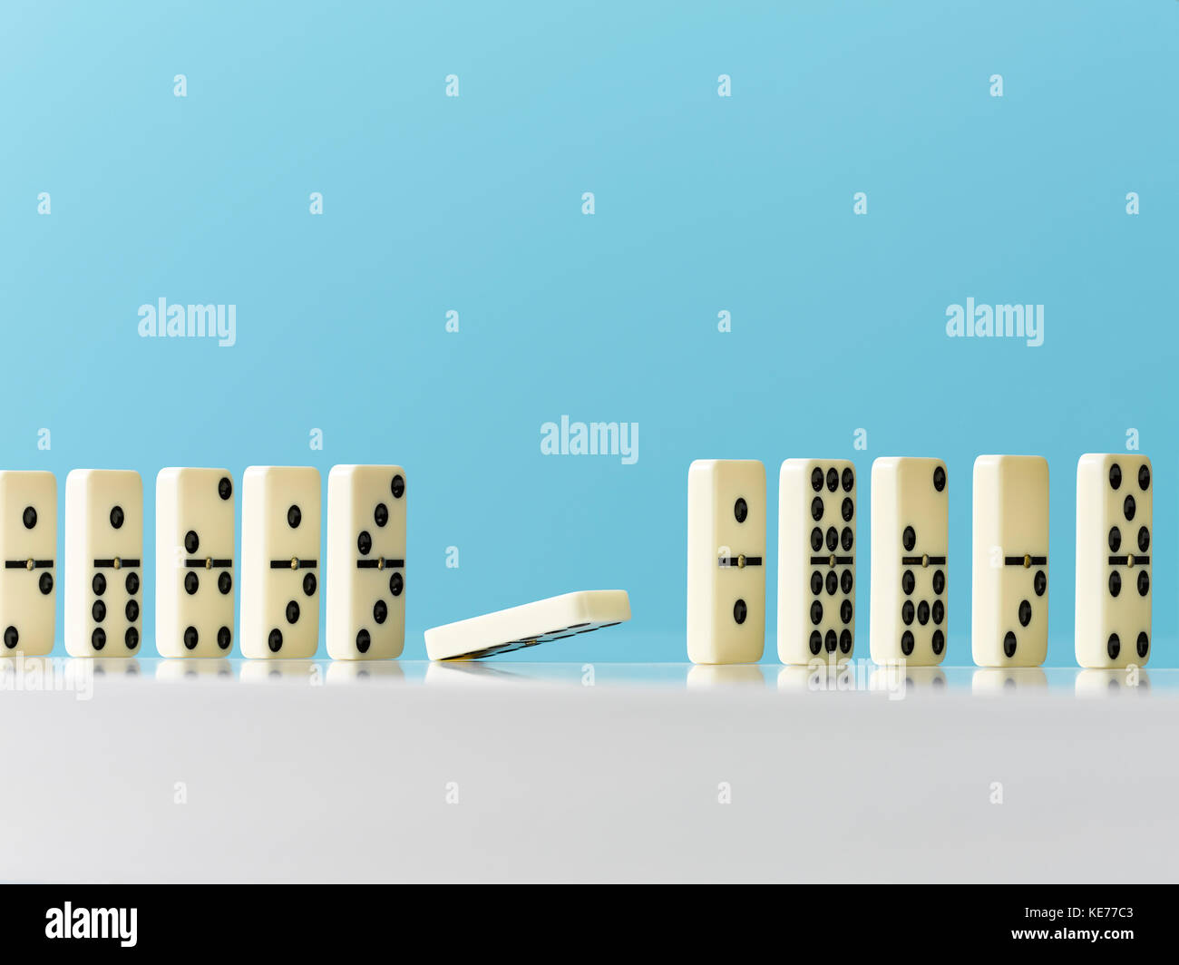 Domino fallen in einer Reihe auf blauem Hintergrund Stockfoto