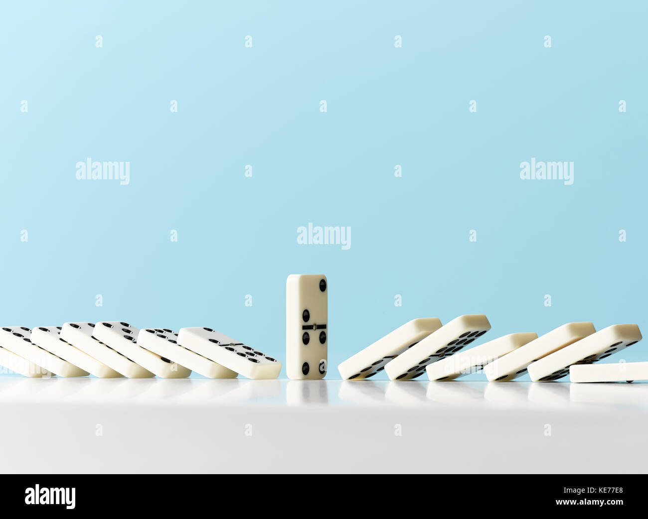 Dominos um ständigen Domino vor blauem Hintergrund fallen Stockfoto