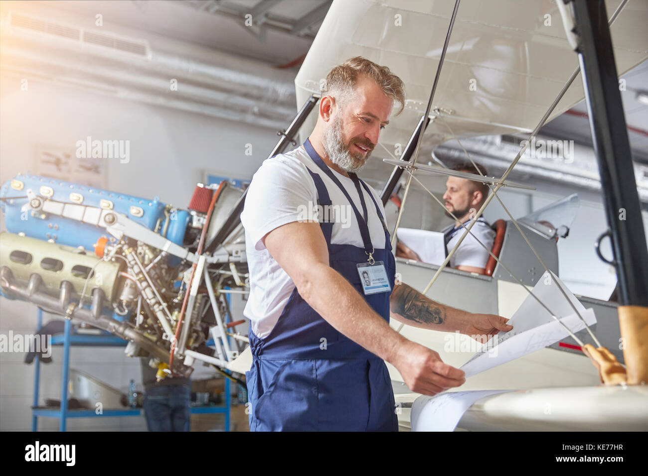 Männlicher Maschinenbauingenieur, der Pläne im Flugzeug im Hangar überprüft Stockfoto