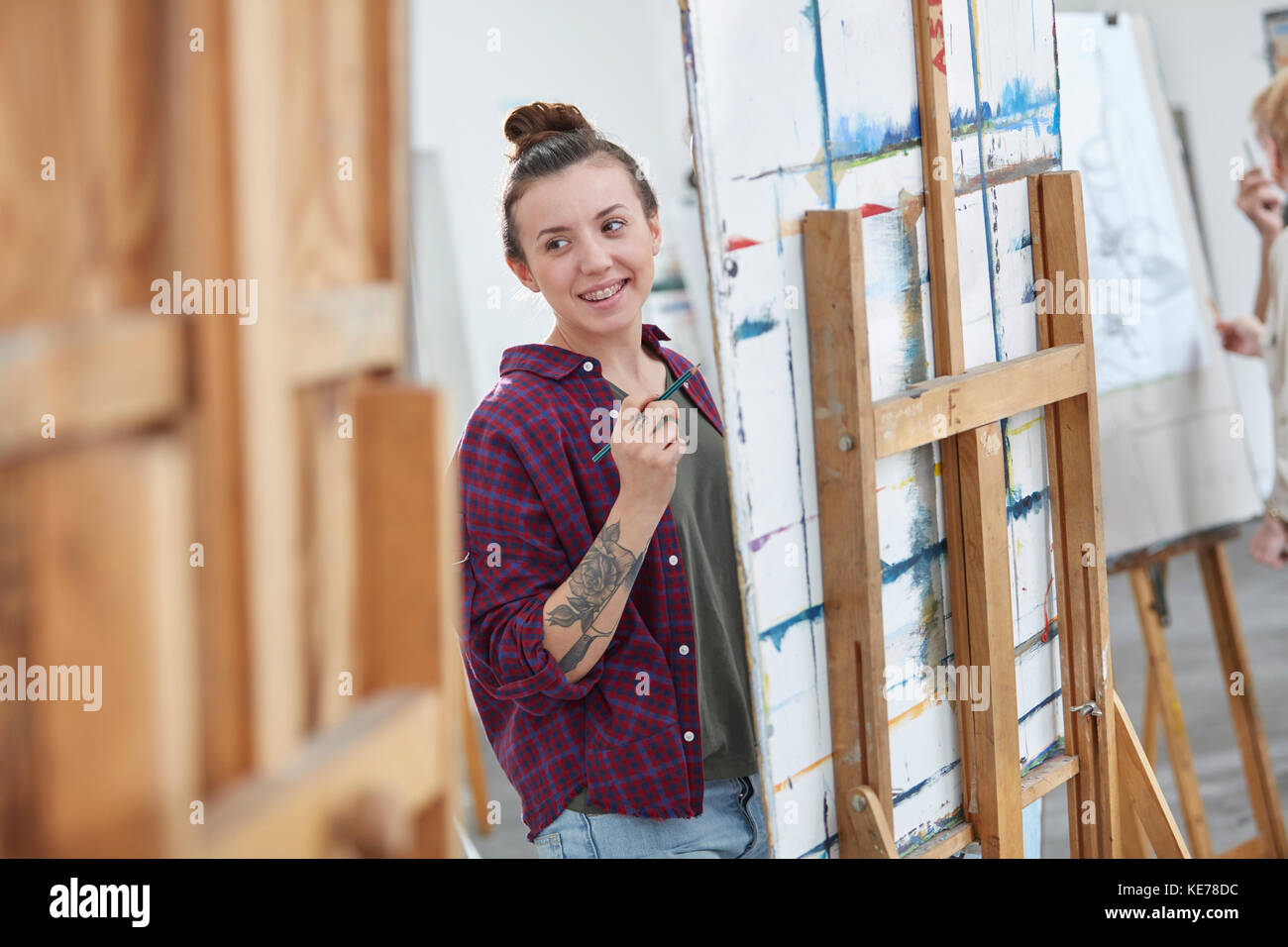 Weibliche Künstlerin Malerei an Staffelei im Kunstklassestudio Stockfoto
