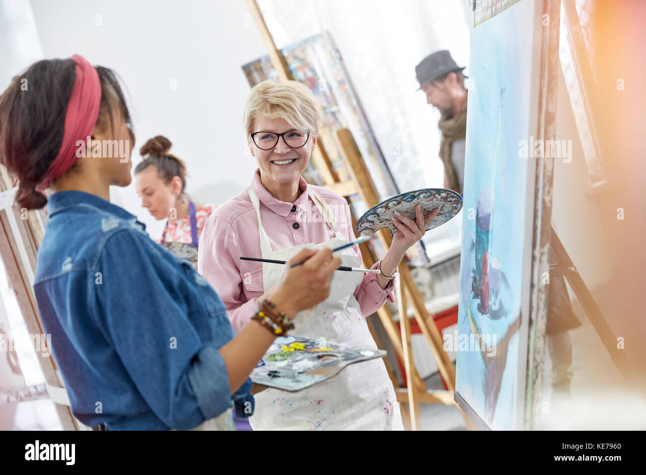 Lächelnde Künstlerinnen mit Pinsel und Paletten Malerei in der Kunst Klasse Studio Stockfoto