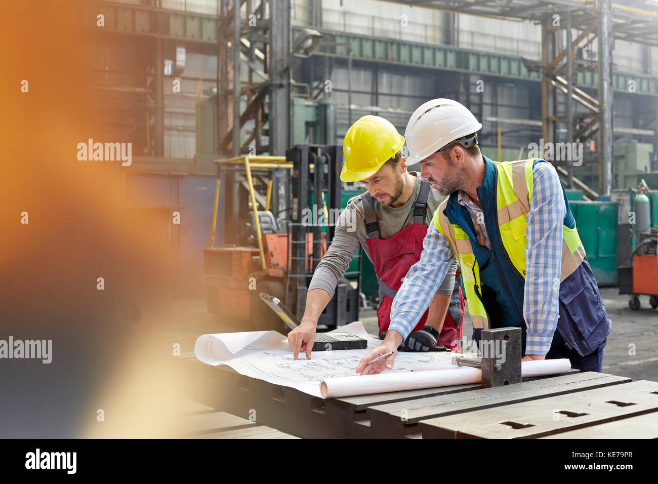 Männliche Ingenieure überprüfen Baupläne im Werk Stockfoto