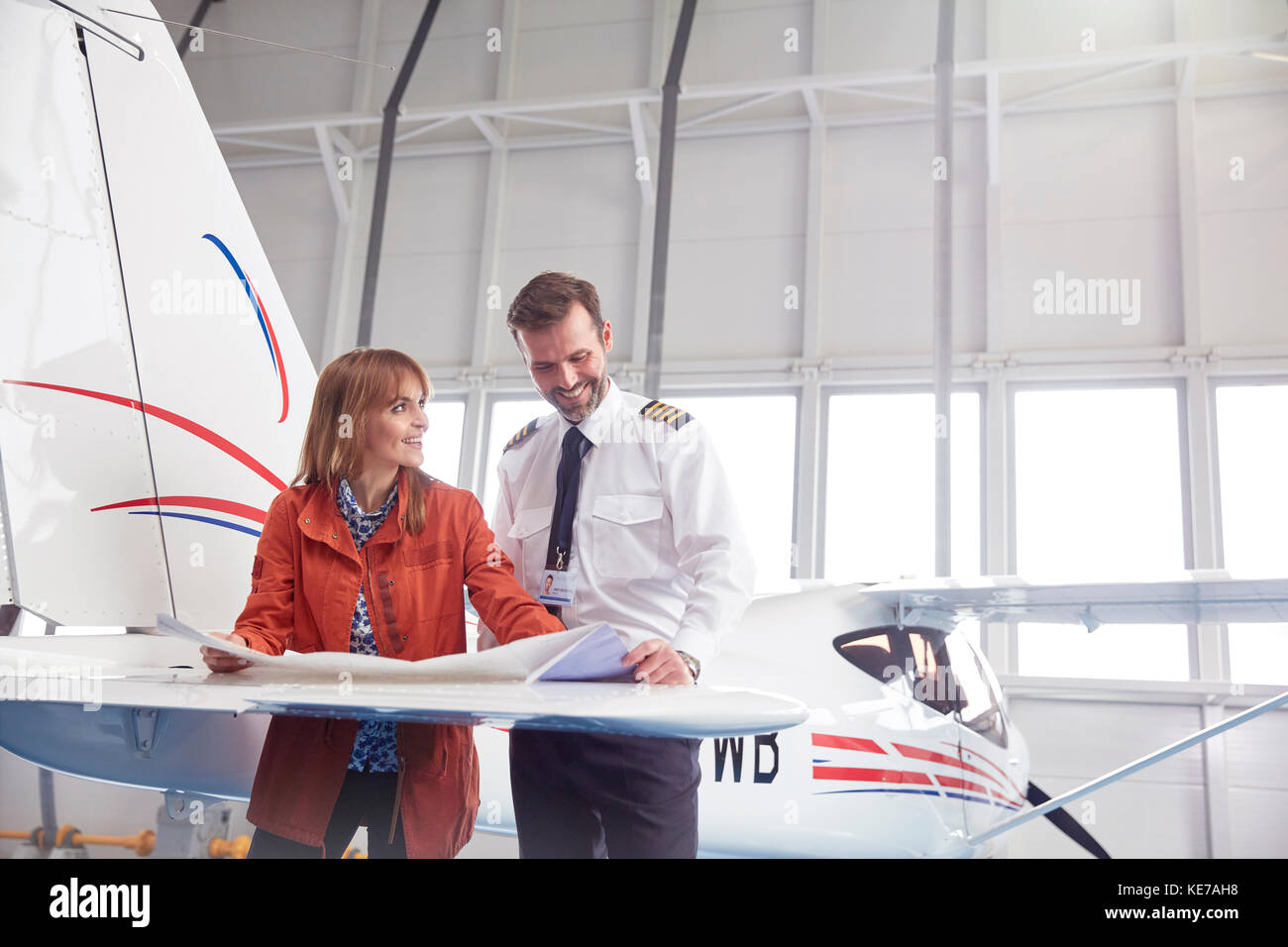 Pilot und Ingenieur Überprüfung Pläne auf Flugzeugflügel in Hangar Stockfoto