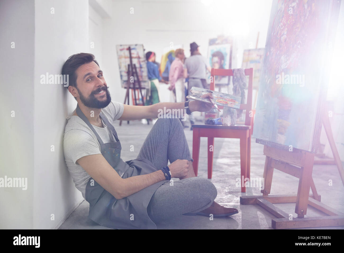 Portrait lächelnder männlicher Künstler mit Palettenmalerei an Staffelei Art Class Studio Stockfoto