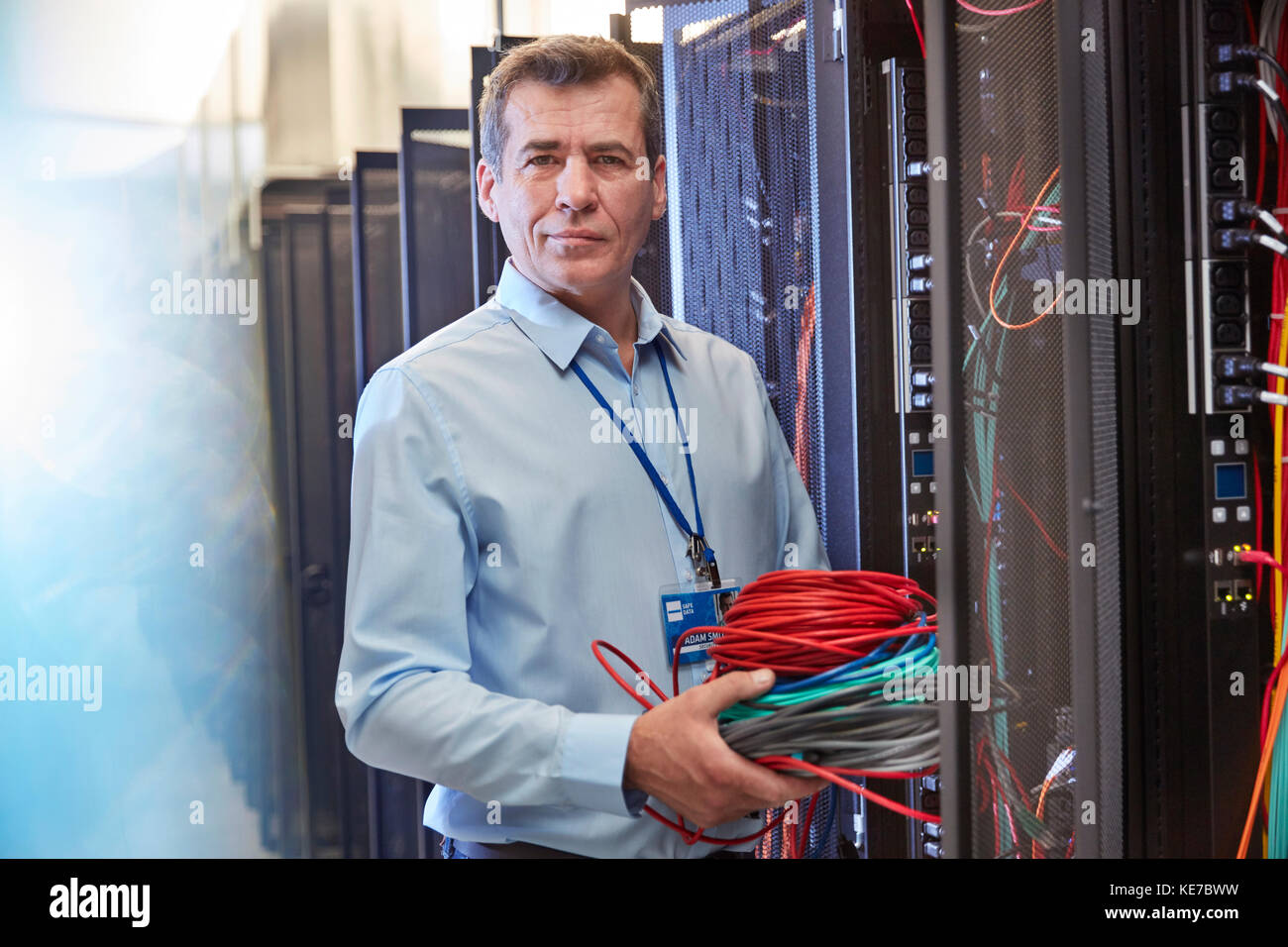 Portrait seriöser IT-Techniker, der Kabel im Serverraum hält Stockfoto