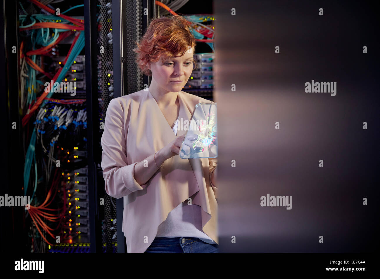 IT-Technikerin mit futuristischem digitalem Tablet im Serverraum Stockfoto