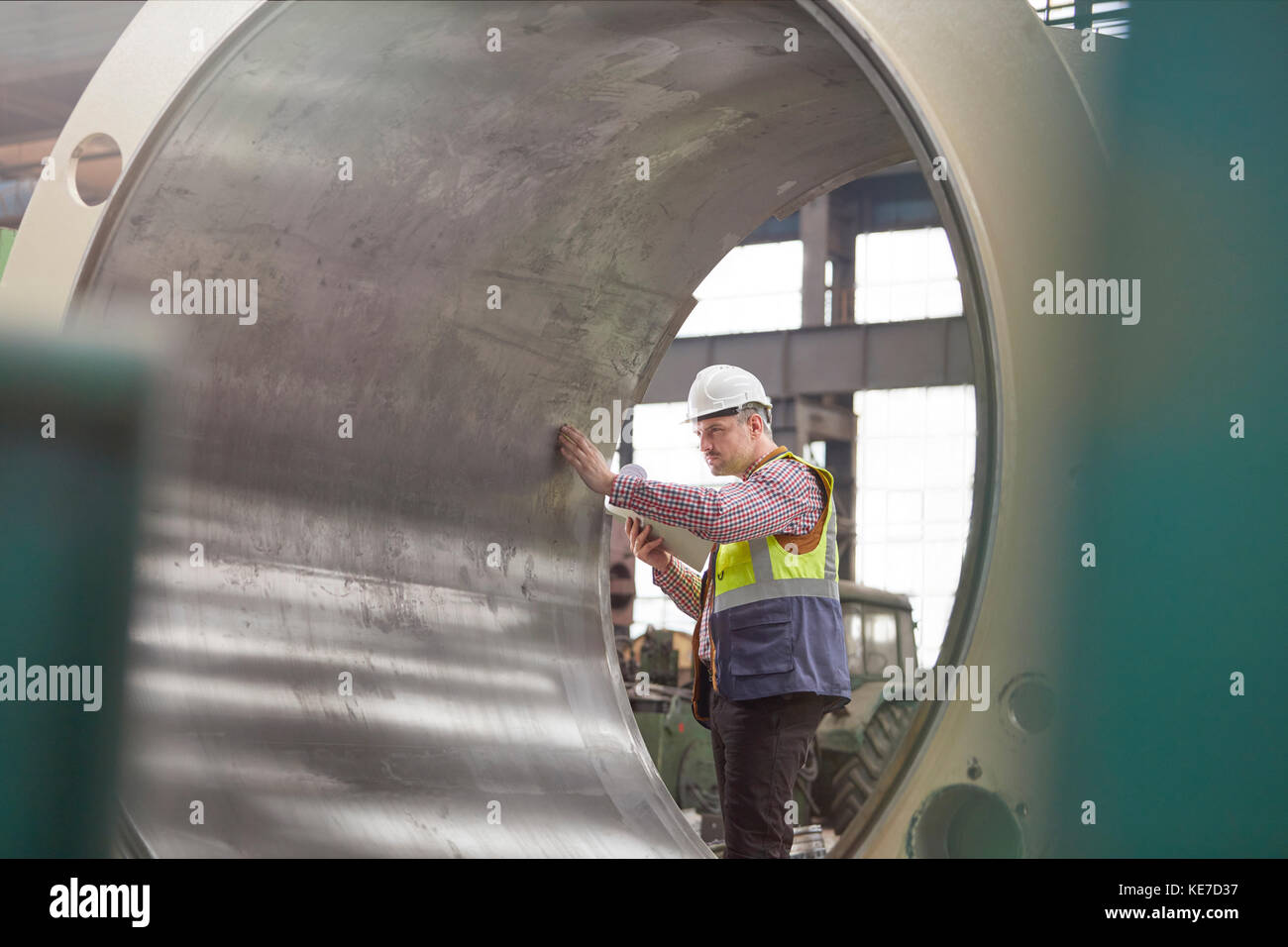 Männlicher Ingenieur, der große Stahlzylinder im Werk untersucht Stockfoto