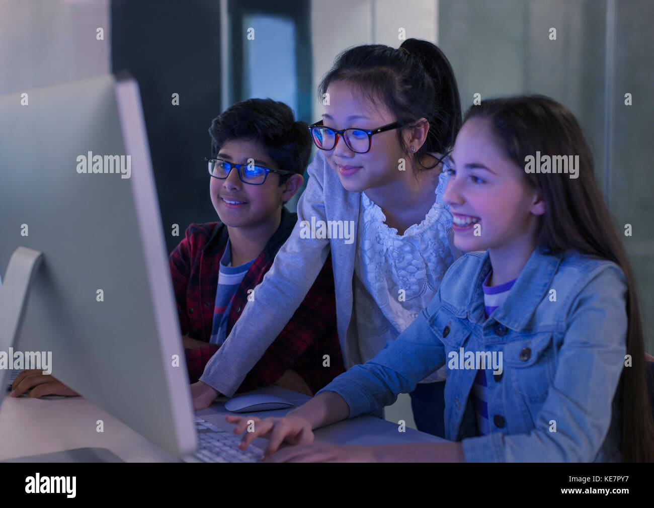 Schüler, die am Computer im dunklen Klassenzimmer forschen Stockfoto