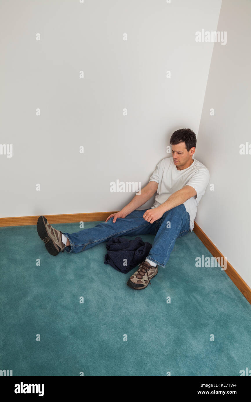 Mittleres Alter Mann sitzt auf dem Boden in der Ecke eines Zimmers, Connecticut, Vereinigte Staaten Von Amerika Stockfoto