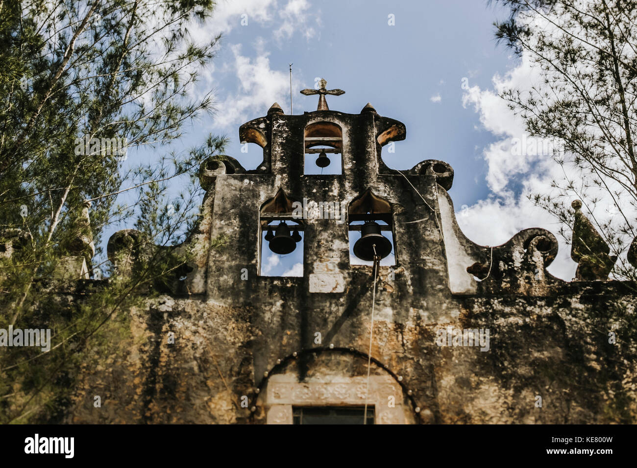 Low Angle View eine verwitterte Wand einer Kapelle mit Glocken und ein Kreuz; Cancun, Mexiko Stockfoto