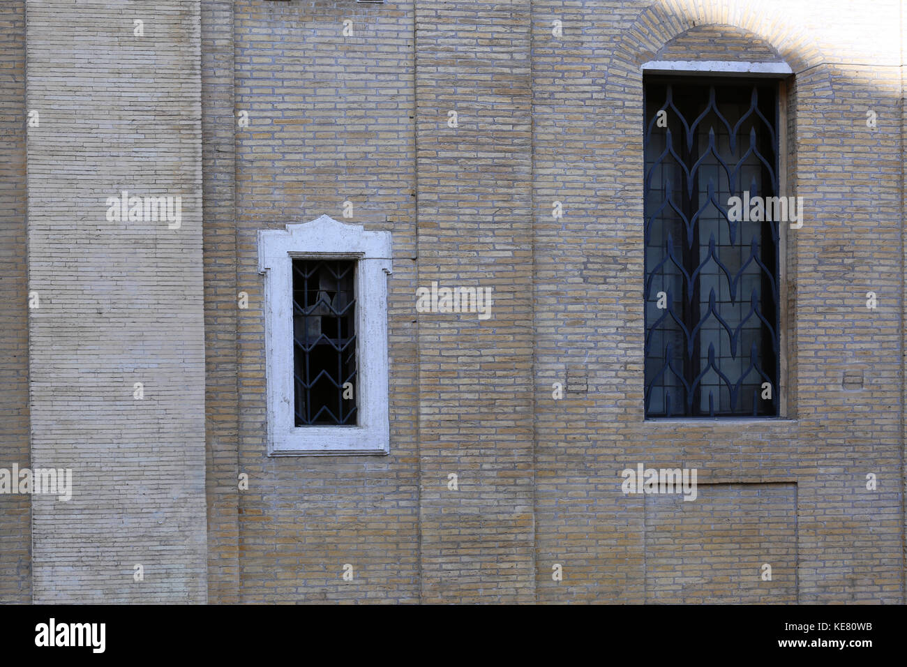 Zwei verschieden grosse Fenster in eine Wand gesetzt von sehr kleinen Steine einer hellen Farbe. Stockfoto