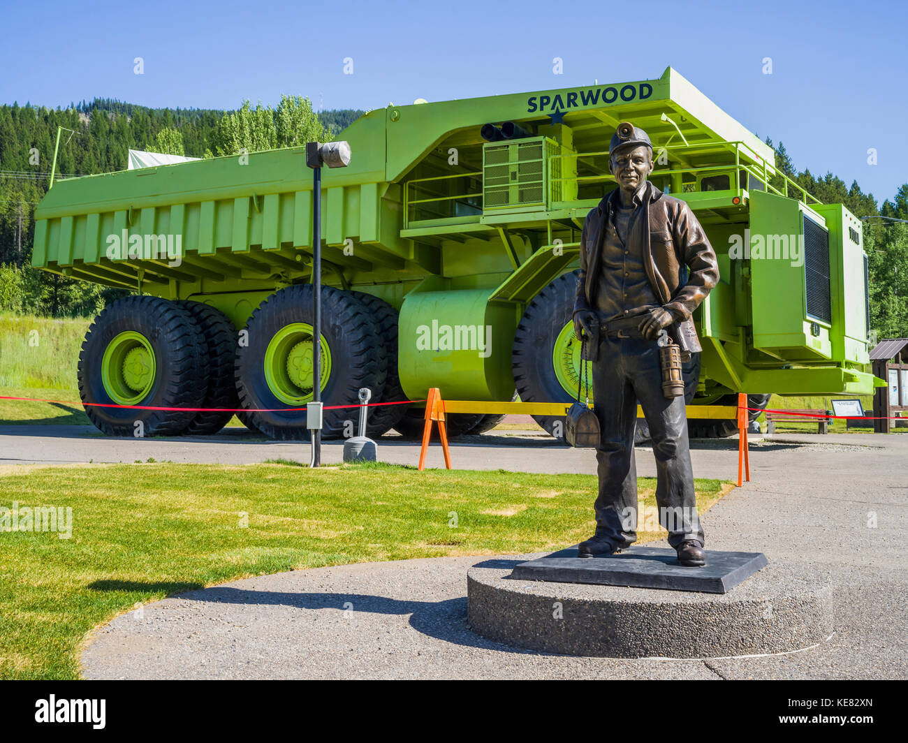 Große grüne Titan Dump Truck auf dem Display mit einer Statue eines Bergmanns im Vordergrund; Sparwood, British Columbia, Kanada Stockfoto
