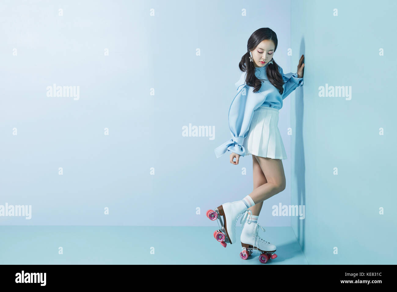 Junge Frau in Rollen skates stehen auf einem Fuß posing nach unten schauen. Stockfoto