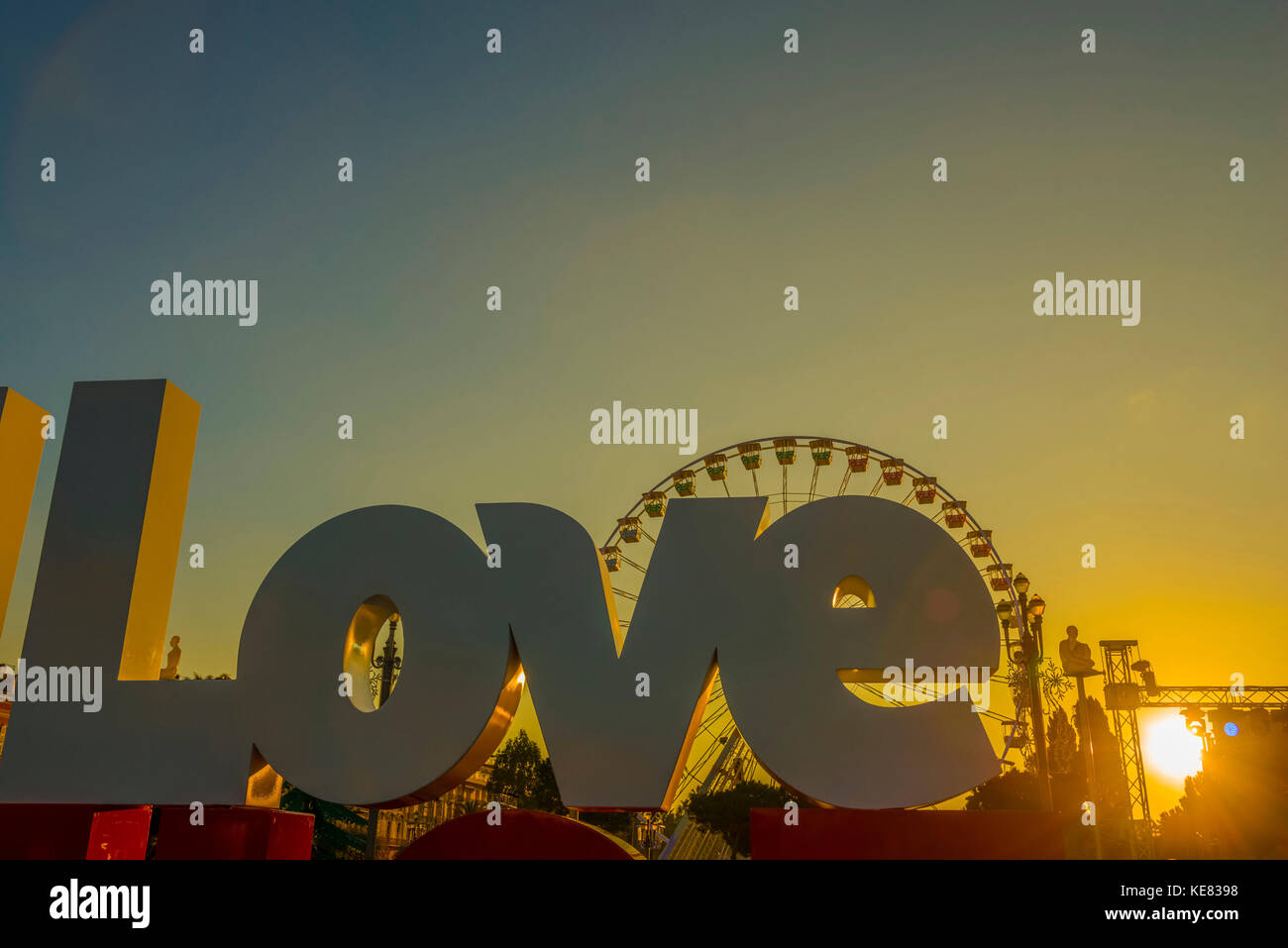 Ein großes Schild lesen Liebe mit einer Silhouette einer Riesenrad gegen einen Goldenen Himmel bei Sonnenuntergang, Place Massena, Nizza, Côte d'Azur, Frankreich Stockfoto