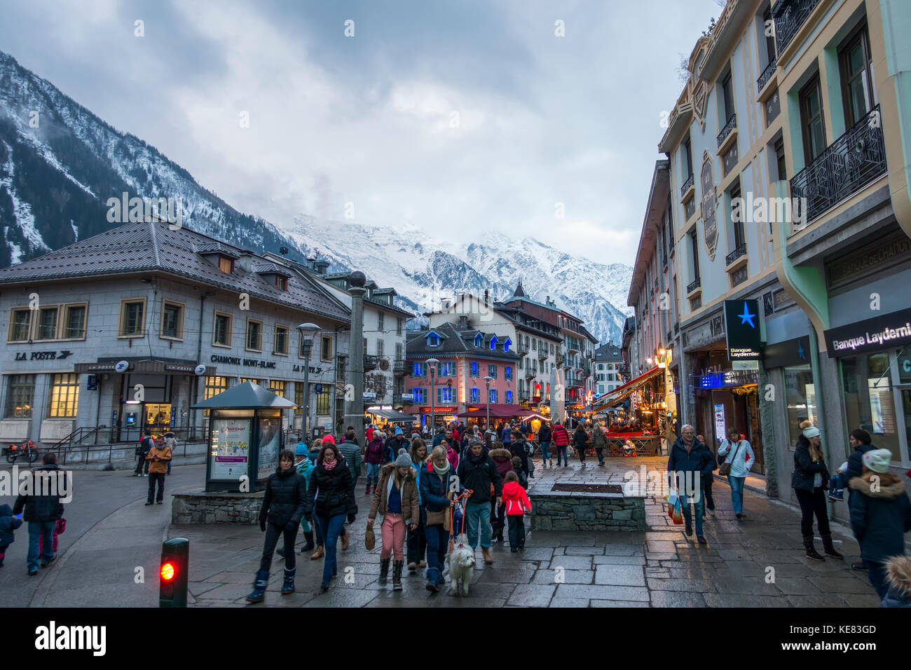 Touristen auf den Straßen neben Geschäften mit Blick auf die Bergkette, Chamonix, Frankreich Stockfoto