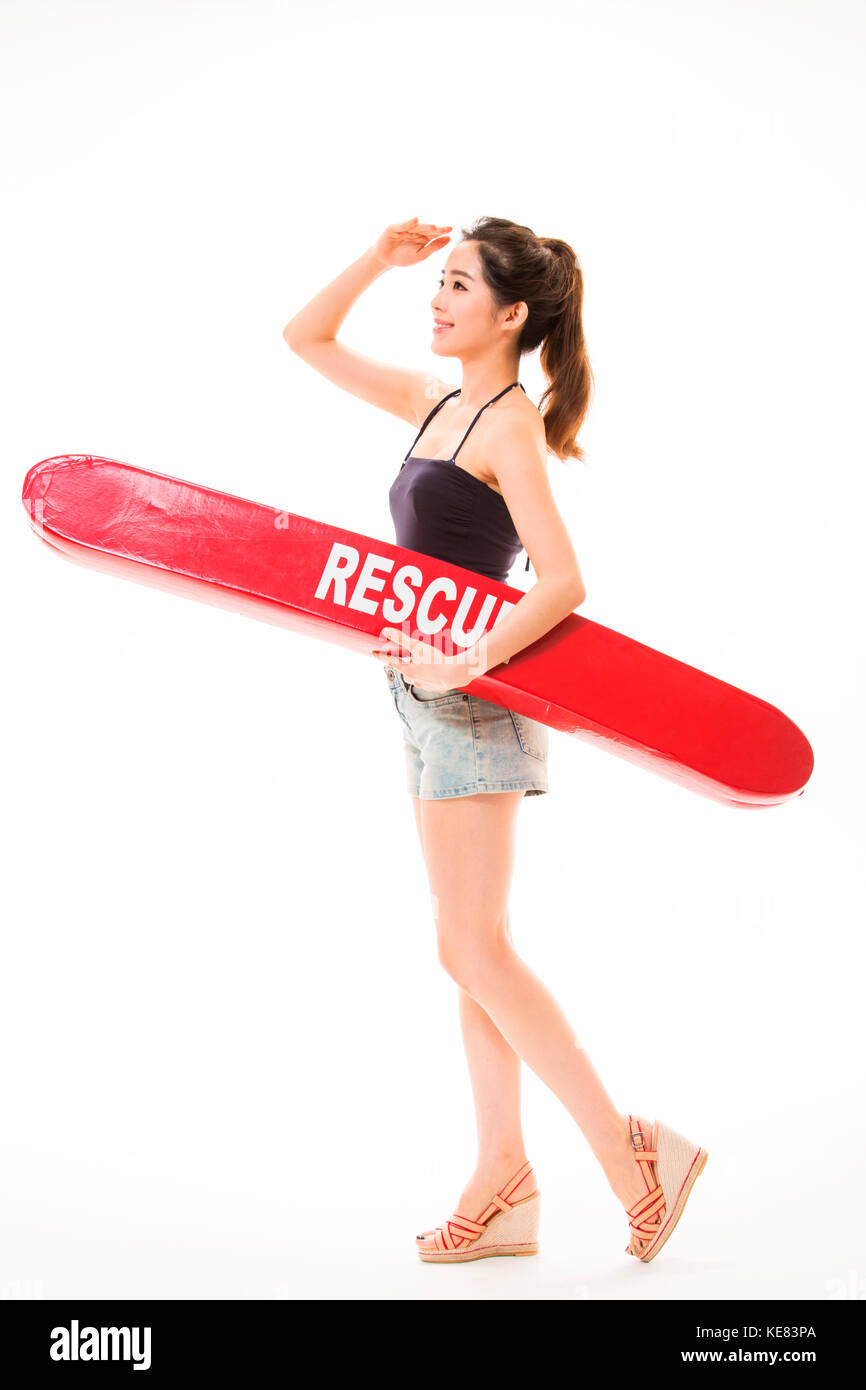 Seitenansicht der junge lächelnde Frau im Sommer Kleidung ständigen Holding eine Surf Board Stockfoto
