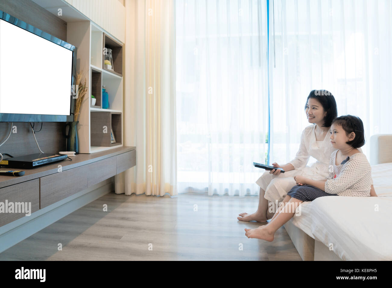 Gerne asiatische Familie Mutter und Tochter sitzen auf einem Sofa, Fernseher mit Flachbildschirm im Wohnzimmer zu Hause. Familie Zeit. Stockfoto