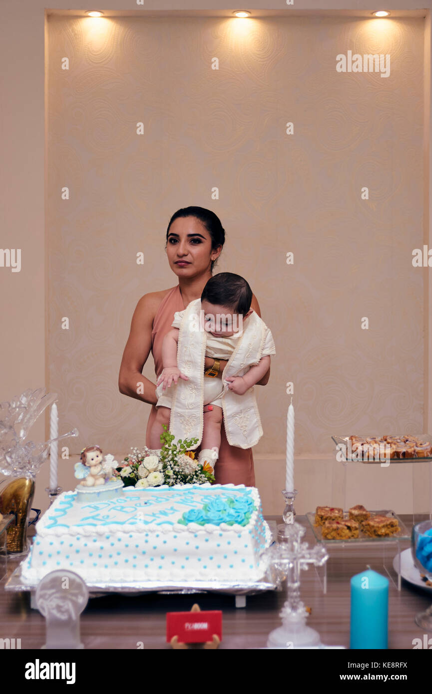 Mutter mit gerade getauft Baby in Armen mit ihrem Foto am Süßigkeiten Tisch gemacht Stockfoto