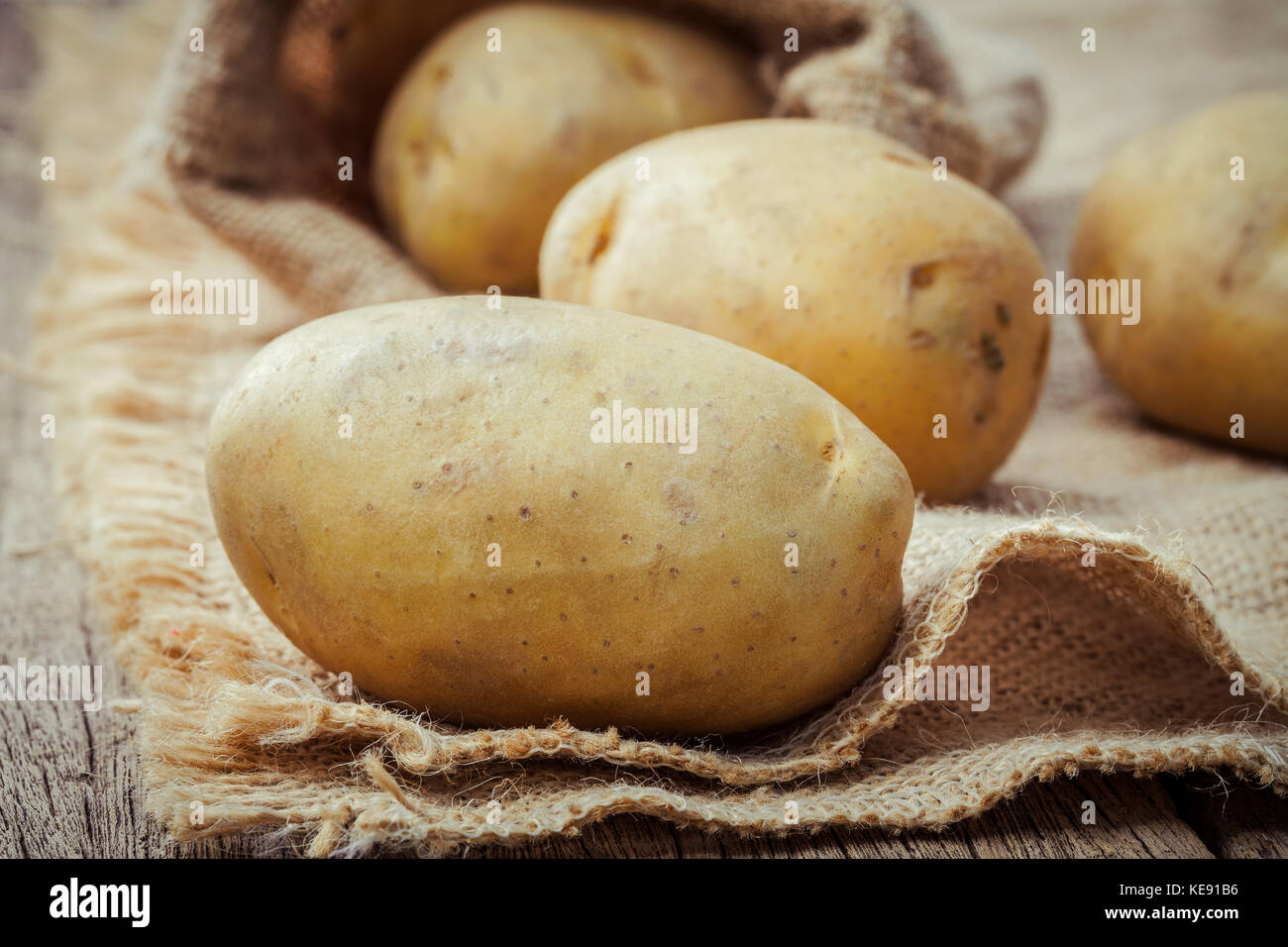 Closeup frische organische Kartoffeln auf Hanf sack Hintergrund. Zeile Biokartoffeln auf alten Holz- Hintergrund. Stockfoto