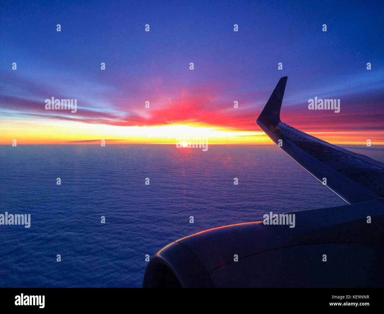 Flügel eines Flugzeugs in Wolken bei Sonnenuntergang. Stockfoto