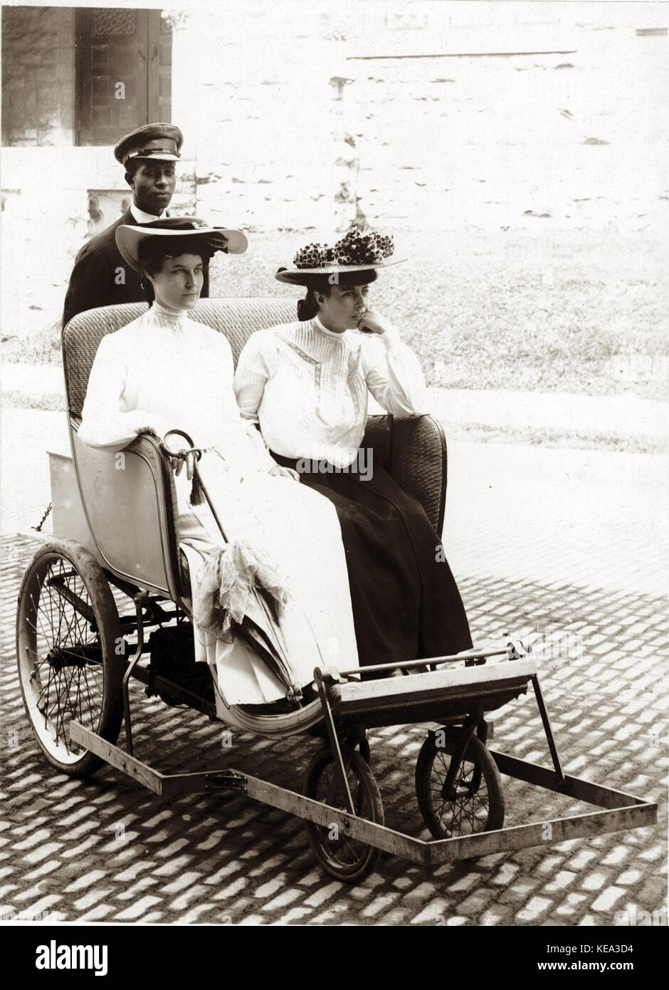 Zwei Frauen in eine Tandemwalze Sessel mit Rädern von einem uniformierten afrikanische amerikanische Mann an der Weltausstellung 1904 Stockfoto