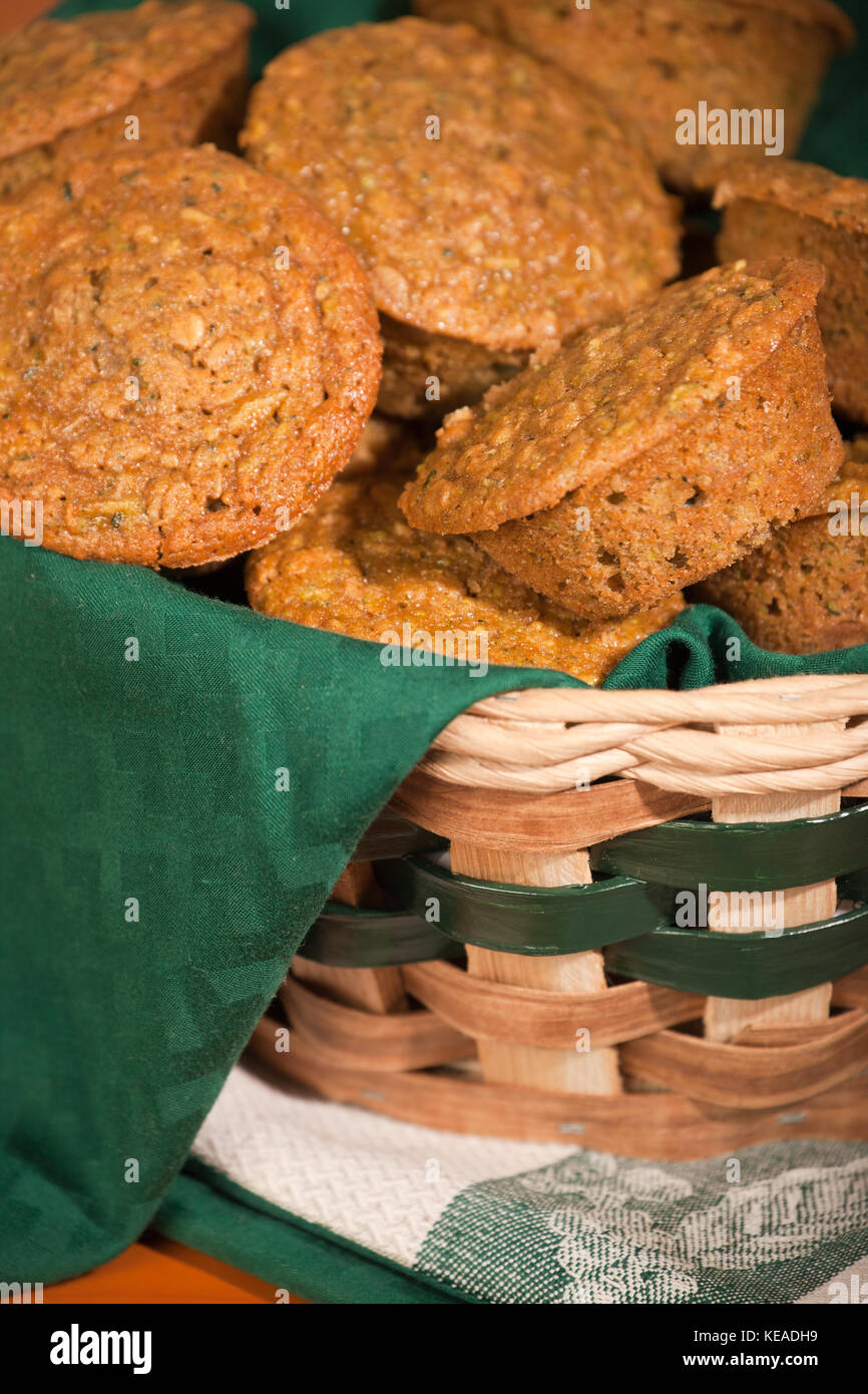 Zucchini Muffins in einem Tuch gestapelt - Weidenkorb gesäumt, ruht auf Kaffee Handtücher auf ein Holz Tisch Stockfoto