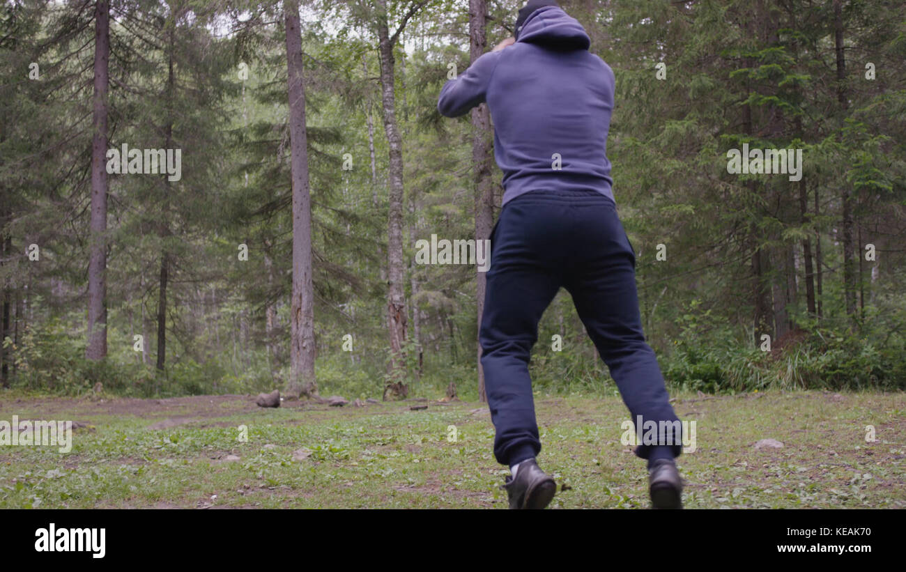 Ein junger Sportler springt, macht Kraftübungen, ein Crossfit-Element. Im Kiefernwald, im Sommer Stockfoto
