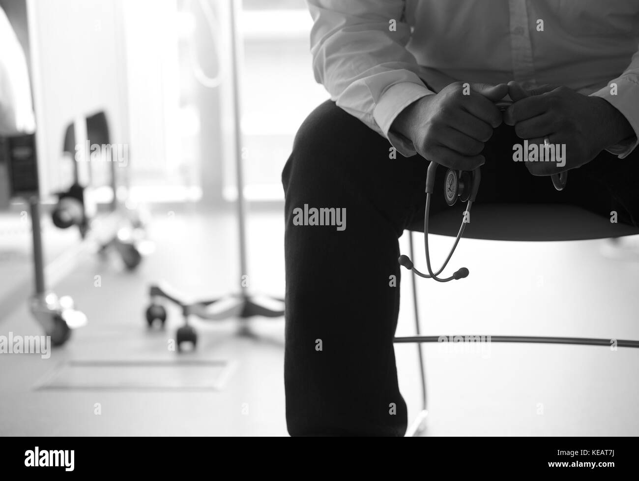 Männliche Ärzte Hände halten Stethoskop mit ward Unscharf im Hintergrund B&W Stockfoto