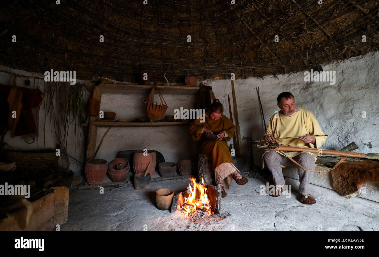 Living History reenactors Mark und Jill Hatch in einem neolithischen Haus während einer Vorschau auf das Fest! Essen in der Stonehenge-Ausstellung in Wiltshire, die zeigt, was die Erbauer des Denkmals aßen und kochten. Stockfoto
