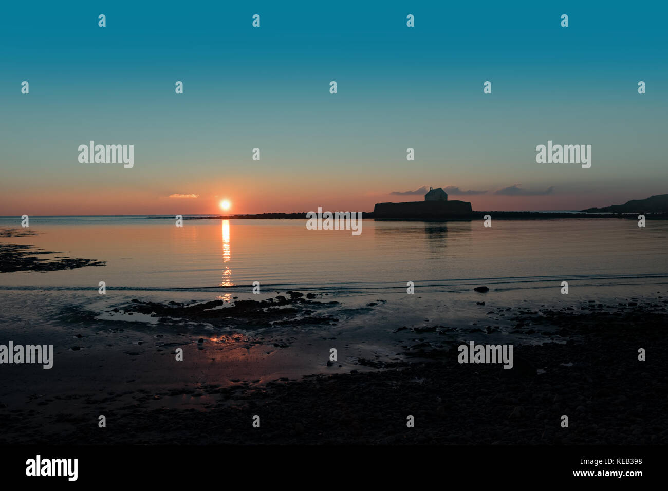 Cwyfan Sonnenuntergang. Die Kapelle im Meer, vor Anglesey, Wales. Stockfoto