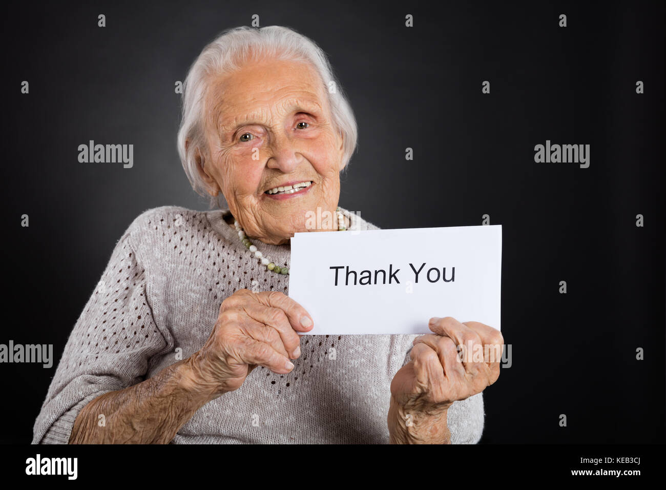 Portrait von lächelnden älteren Frau, vielen Dank Karte über grauer Hintergrund Stockfoto