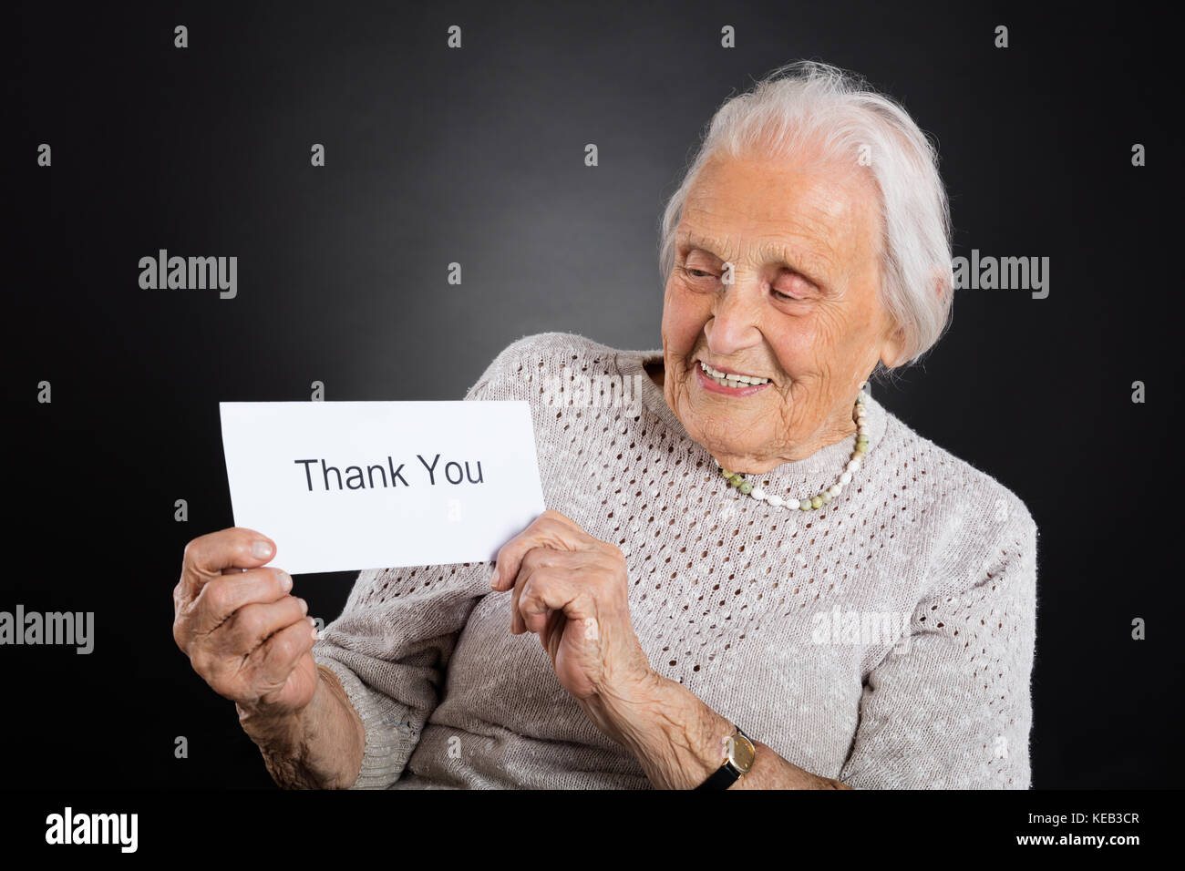 Portrait von lächelnden älteren Frau, vielen Dank Karte über grauer Hintergrund Stockfoto