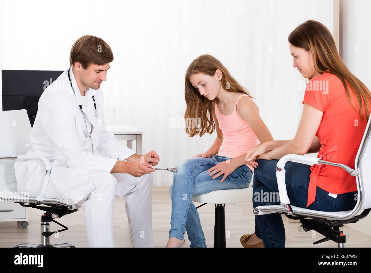 Junge männliche Neurologen untersuchen Knie Reflex auf Mädchen in der Klinik Stockfoto