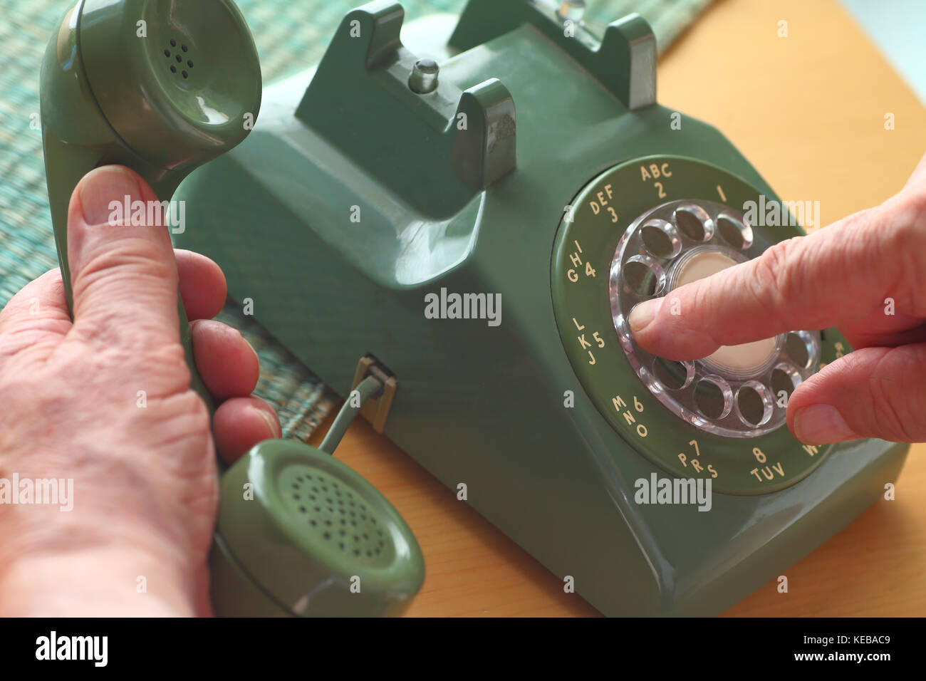 Ein älterer Mann wählt eine Nummer auf einem vintage Festnetztelefon. Stockfoto
