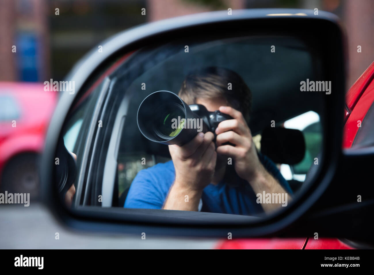 Privatdetektiv Sitzen im Auto Fotografieren reflektiert im Außenspiegel Stockfoto