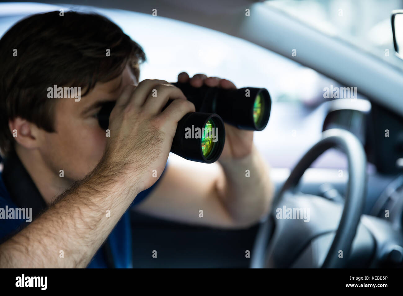 Privatdetektiv Blick durch ein Fernglas im Auto sitzen Stockfoto