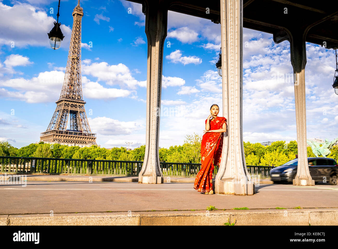 Schöne junge Frau in einem roten Sari auf der Pont Bir-Hakeim mit dem Eiffelturm im Hintergrund in Paris gekleidet Stockfoto