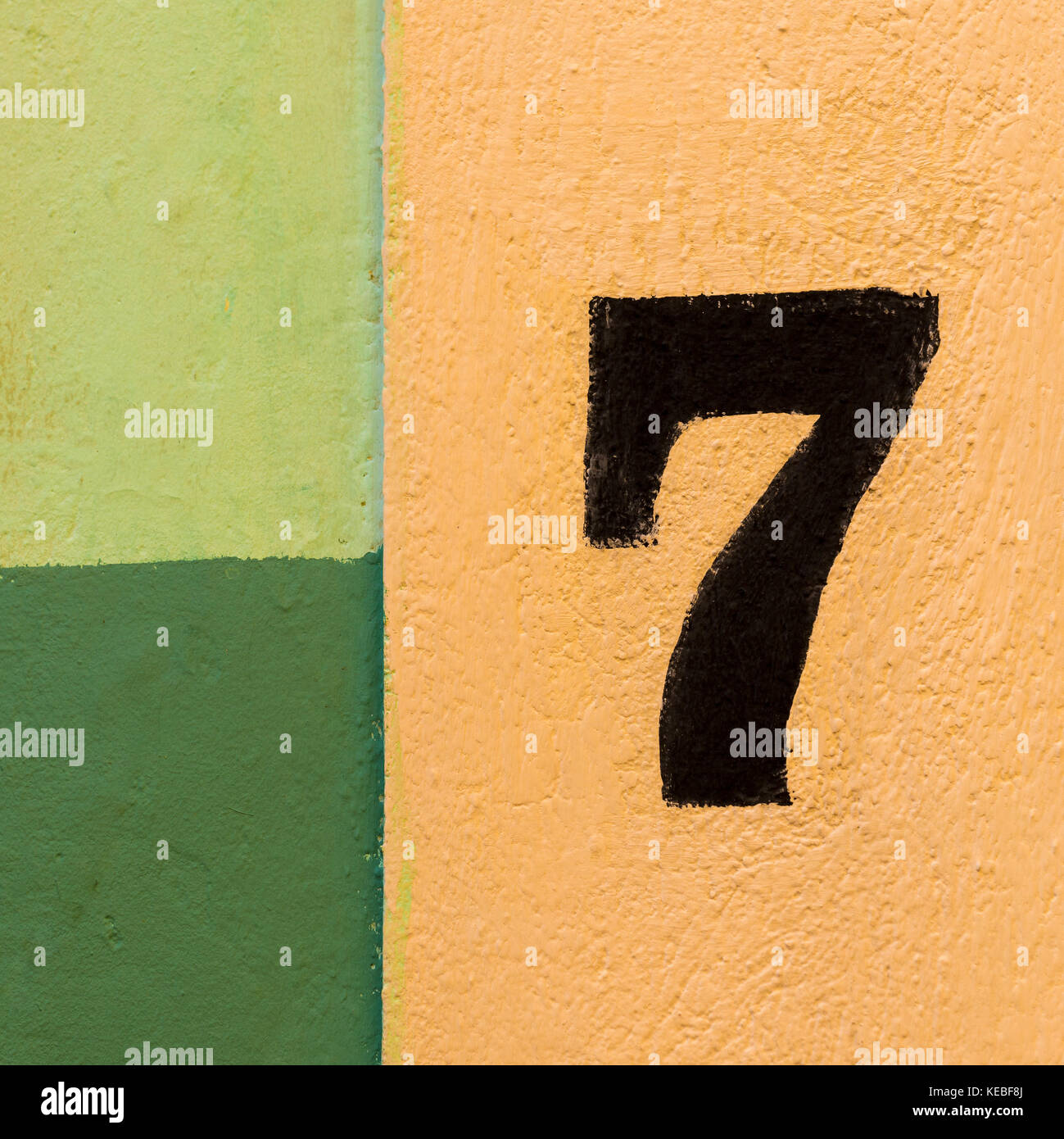 Die Zahl Sieben auf einem farbenfrohen Wand von gelben und grünen Flecken bemalt. Stockfoto