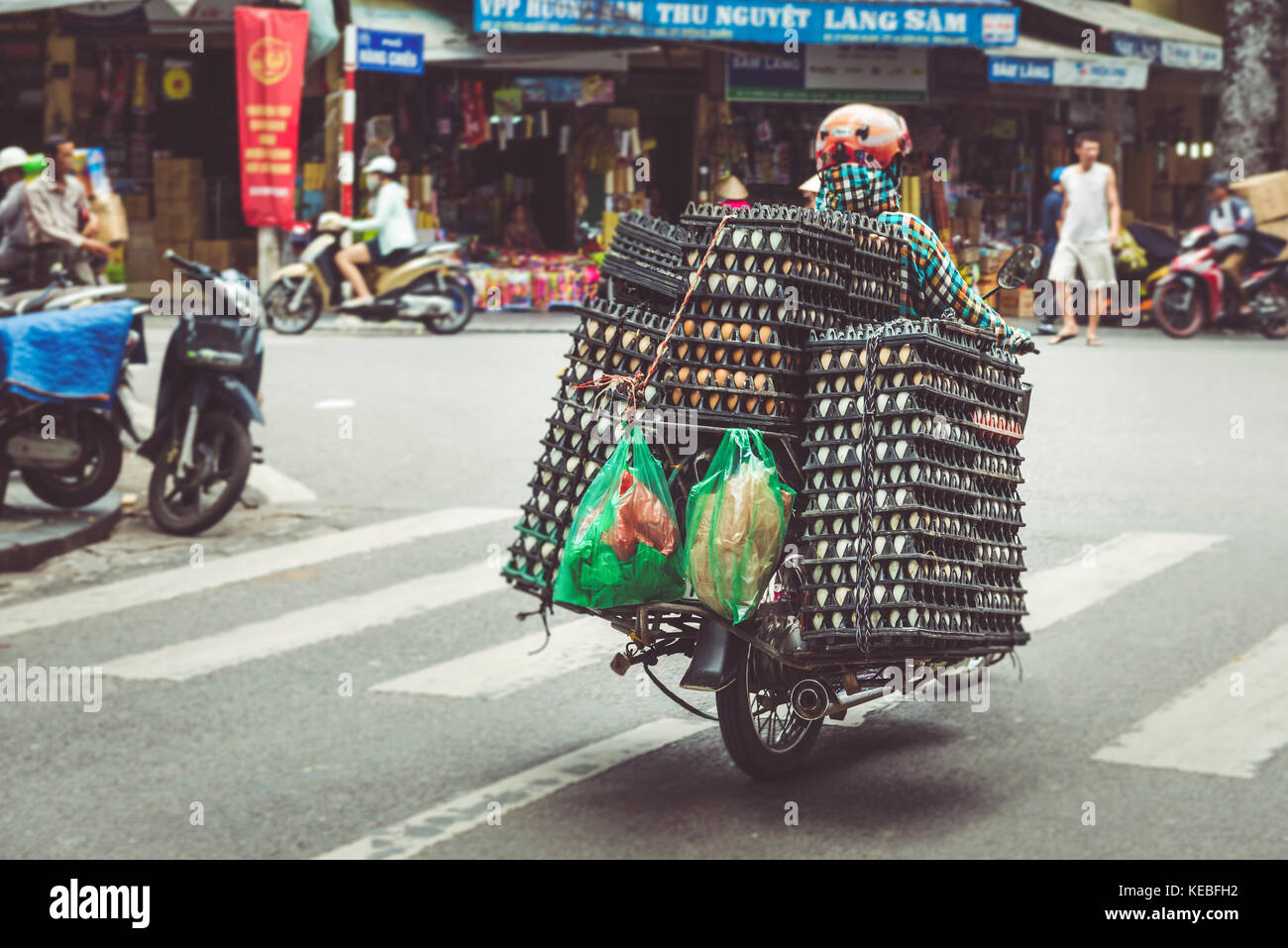 Ein Bauer bringt seine Eier auf einem Moped durch die belebten Straßen der Altstadt von Hanoi Quartal Stockfoto