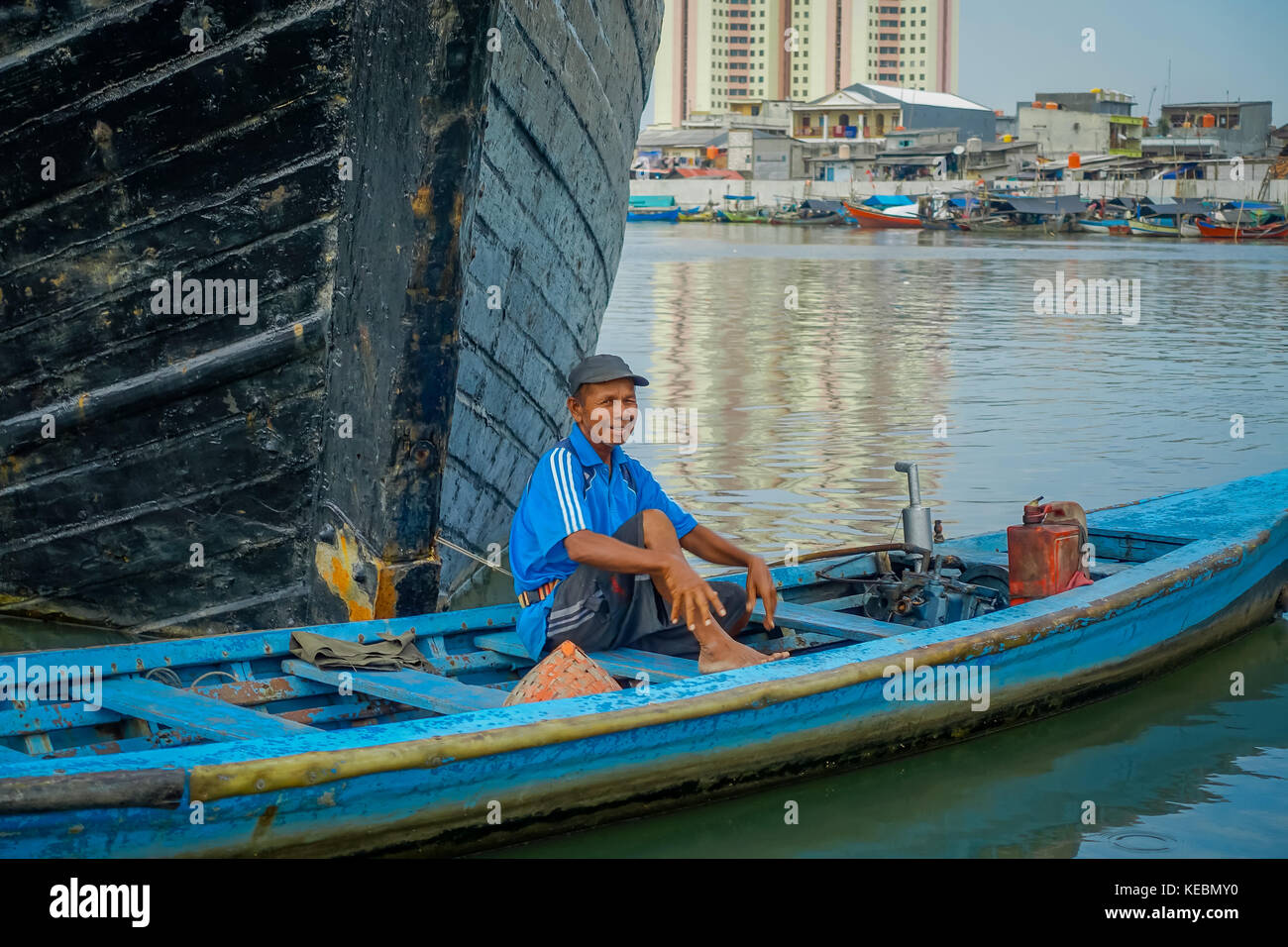 Jakarta, Indonesien - 3. März 2017: Kleine blaue Boot mit lokalen happy Fisherman innen sitzen, vorbei an Vor grösseres Boot Stockfoto