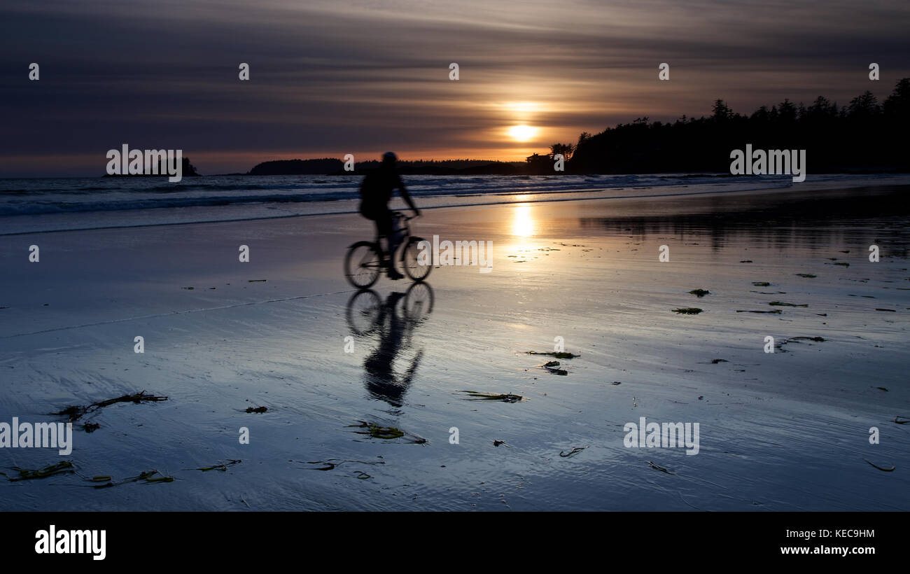 Ein Radfahrer fährt entlang Chesterman Beach, Vancouver Island bei Sonnenuntergang. Stockfoto
