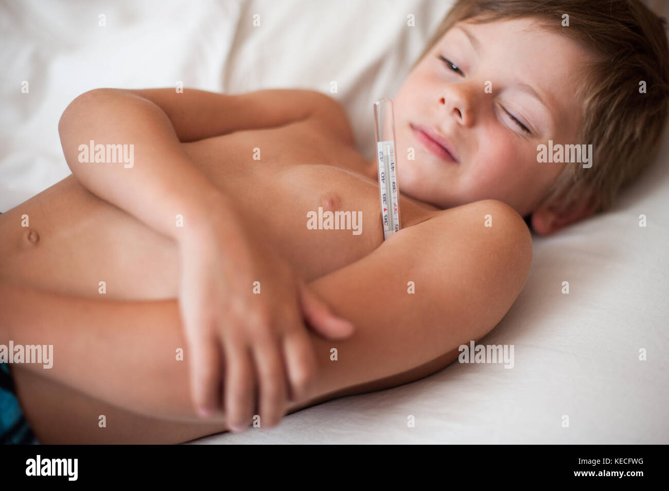 Kranken kleinen Jungen mit einem Thermometer in der Achselhöhle liegend Stockfoto