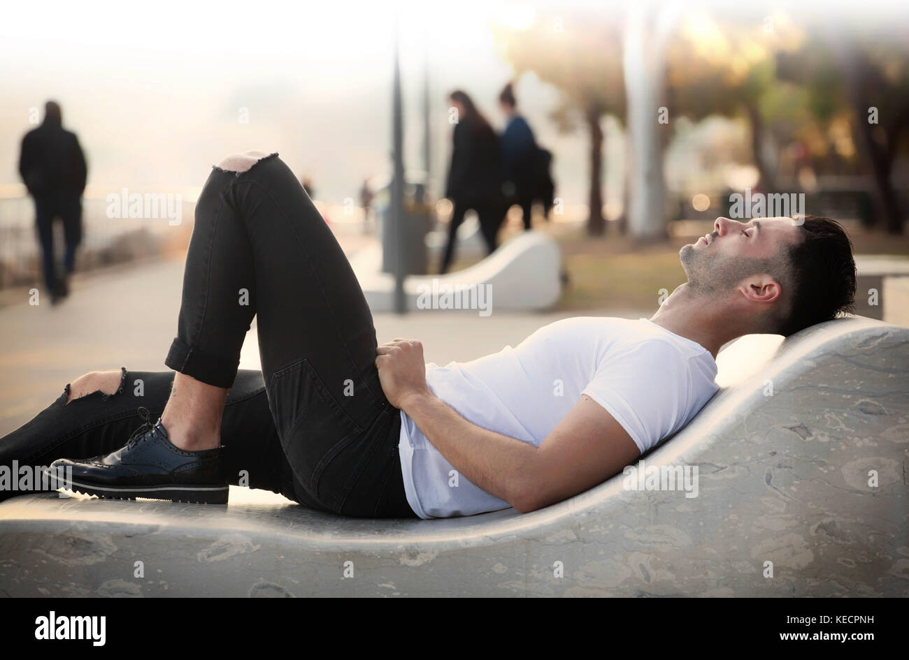 Porträt einer schönen jungen Mann in der Nähe des Meeres liegt auf einer Bank in Entspannung Stockfoto