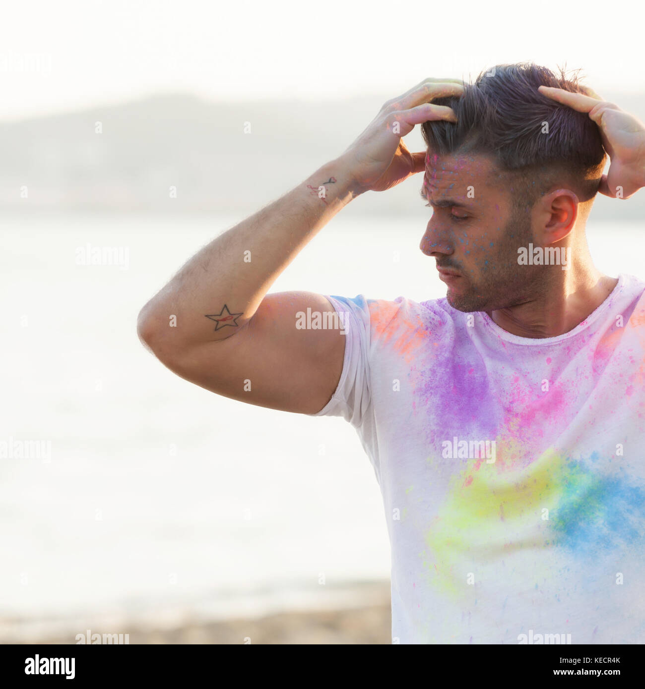 Porträt einer schönen jungen Mann bei Sonnenuntergang mit farbigem Pulver. Stockfoto