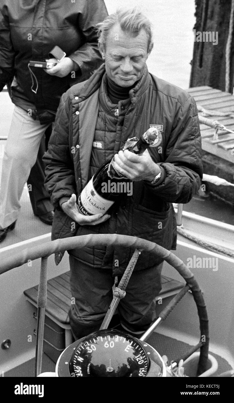 AJAXNETPHOTO. - 29. März, 1982. GOSPORT, England. - WHITBREAD WORLD RACE - GESAMTSIEGER FLYER SKIPPER CORNELIS VAN RIETSCHOTEN ERWÄGT eine Flasche Champagner AN BORD DER YACHT BEI DER ANKUNFT. Foto: Jonathan Eastland/AJAX REF: 822903418 Stockfoto